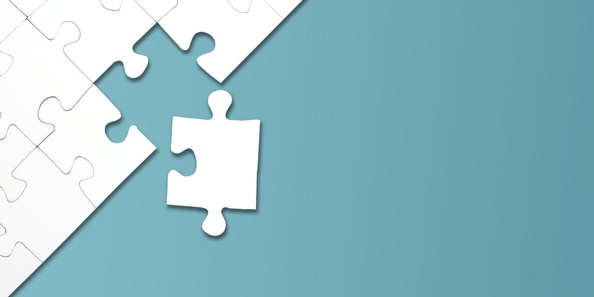 A white jigsaw puzzle against a blue background with one piece missing, but nearby