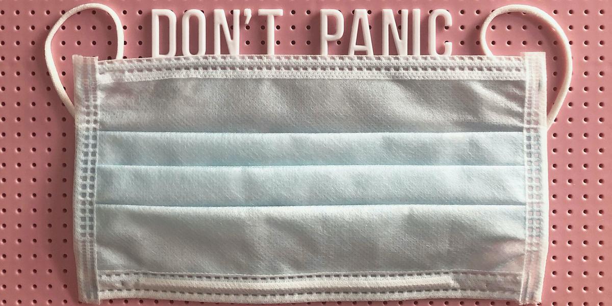 A mask against a pink background with text across the top that says, "Don't panic"