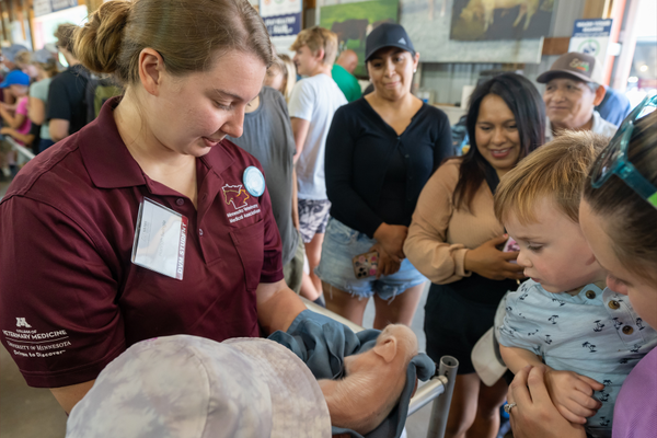 College of Veterinary Medicine DVM student Hannah Swingle shows a newborn piglet to a crowd at the Minnesota State Fair's Miracle of Birth Center. 