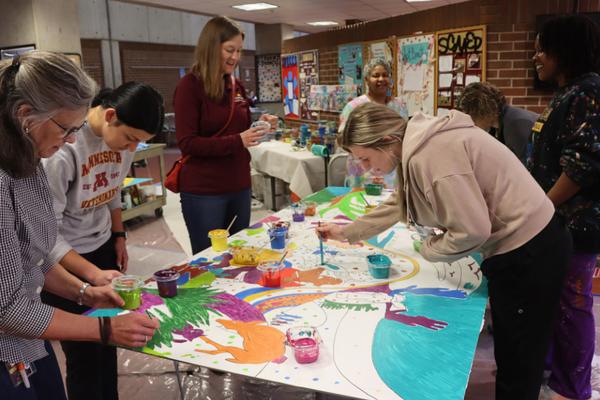 College of Veterinary Medicine faculty, staff, and students paint portions of a mural. 