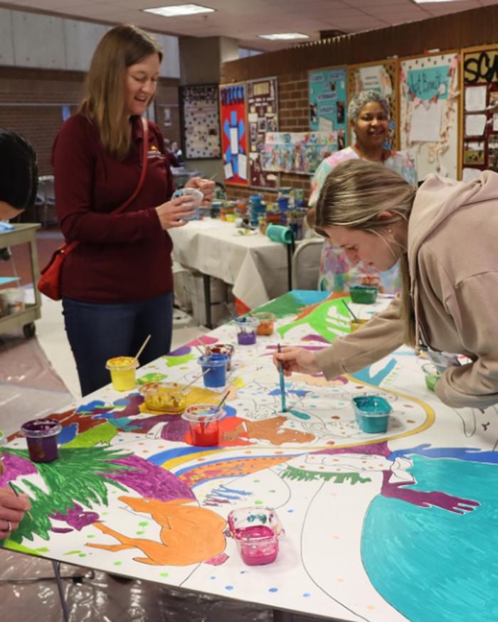 College of Veterinary Medicine faculty, staff, and students paint portions of a mural. 