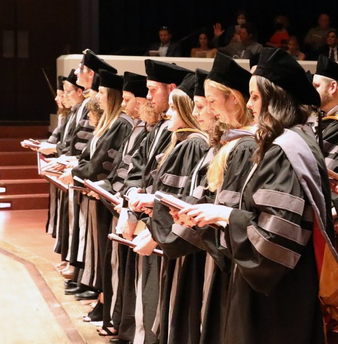 Graduates stand at commencement